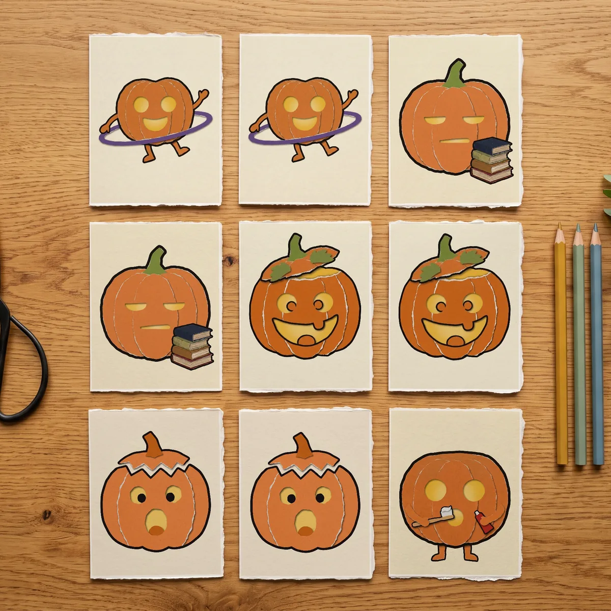 9 printed cards from Jack-o'-Lantern Mini Memory Game laid out in a three-by-three grid on an oak table, including carved pumpkin zigzag lid gasp, pumpkin holding paper scroll, with craft scissors and three pencils beside them.
